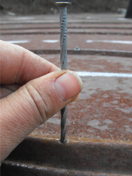 Making a pilot hole in a tin roof with a nail.