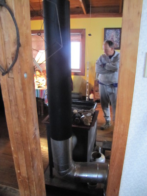 Warm air being heated in a sleeve around the wood stove chimney
