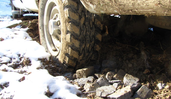 close up of truck stuck in the mud with crushed cinder block pieces piled up to help increase traction