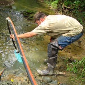 man handling a pump into a creek