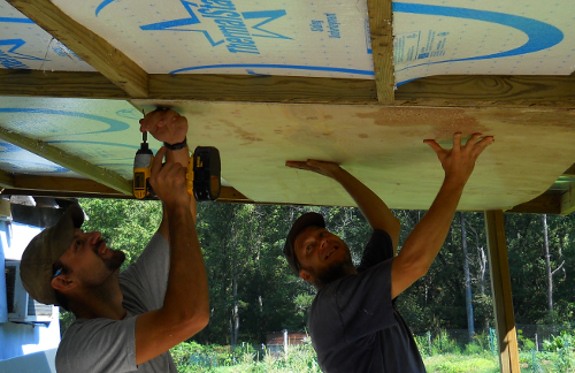 holding up plywood panels for ceiling insulation installation