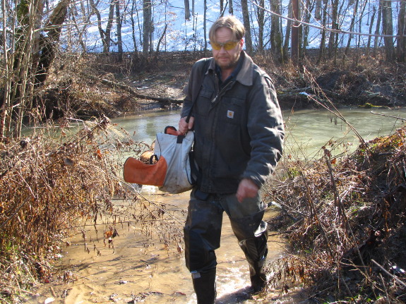crossing creek with Stihl chainsaw in carry bag