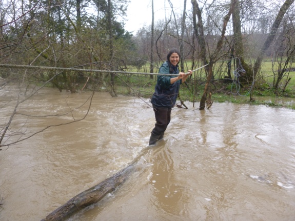 Anna crossing creek on log with rope