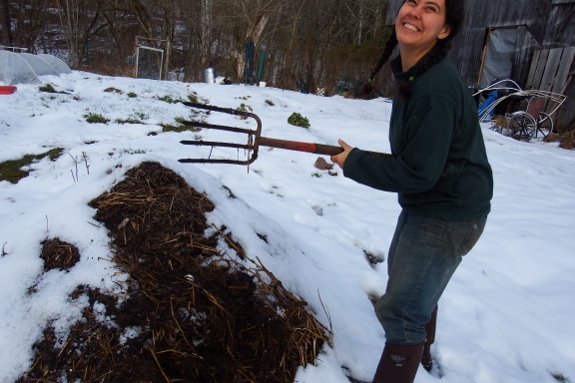 Anna turning compost with a smile on her face
