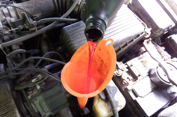 Pouring transmission fluid into a funnel going into the dip stick hole.